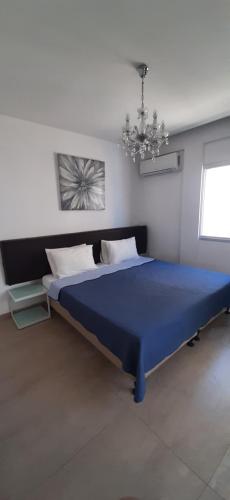 a bedroom with a blue bed and a chandelier at P L PANAGIOTIS Apartment in Larnaka