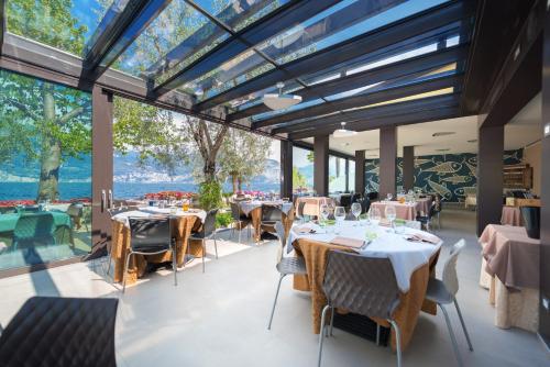 a restaurant with tables and chairs and large windows at Locanda Fassa in Brenzone sul Garda