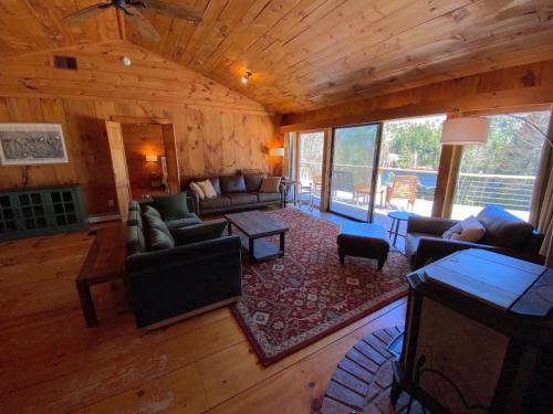 a living room with couches and chairs in a cabin at Amazing lakefront home in the White Mountains with game room theater 51PR in Whitefield
