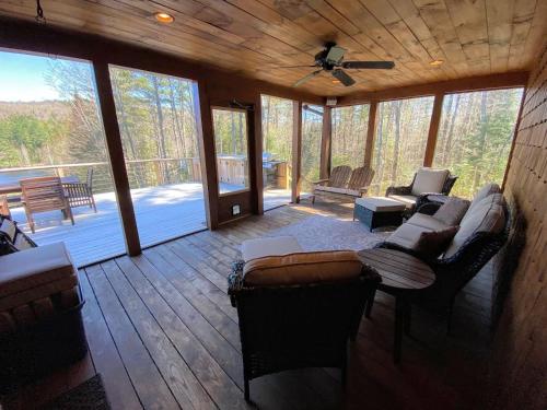 a screened in porch with couches and a living room at Amazing lakefront home in the White Mountains with game room theater 51PR in Whitefield