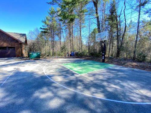 a basketball court in a driveway with a basketball hoop at Amazing lakefront home in the White Mountains with game room theater 51PR in Whitefield