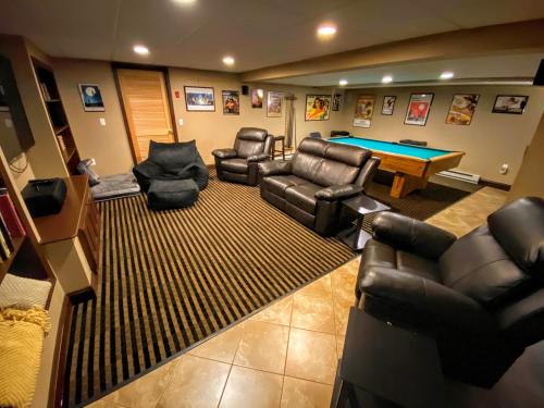 a living room with couches and a pool table at Amazing lakefront home in the White Mountains with game room theater 51PR in Whitefield