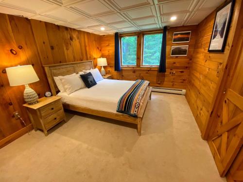 a bedroom with a bed in a room with wooden walls at Amazing lakefront home in the White Mountains with game room theater 51PR in Whitefield