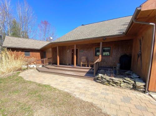a home with a large porch and a house at Amazing lakefront home in the White Mountains with game room theater 51PR in Whitefield