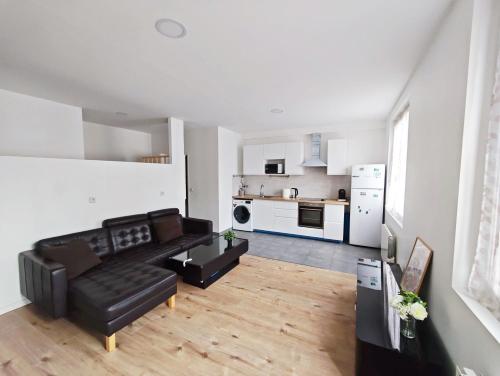 un salon avec un canapé noir et une cuisine dans l'établissement Comfortable Loft and apartment for 2 or 4 persons, à Alfortville