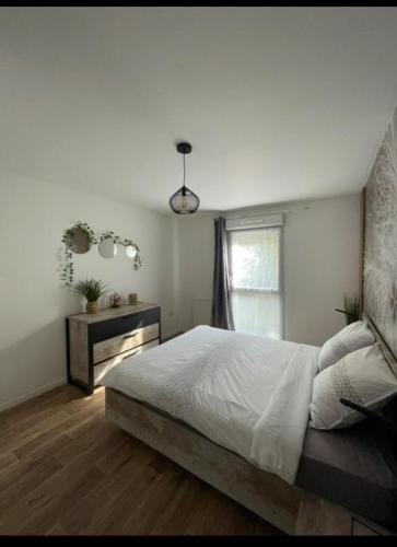 une chambre avec un grand lit et une fenêtre dans l'établissement Appart Cosy de Kalou, à Colombelles