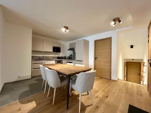 une cuisine et une salle à manger avec une table et des chaises en bois dans l'établissement Homency - Résidence L'Expression D02, à L'Alpe-d'Huez