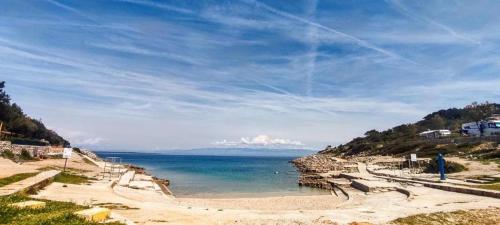 a person standing on a beach near the water at Sea view Anika by Vellaris, Luxury Mobile Home in Mali Lošinj