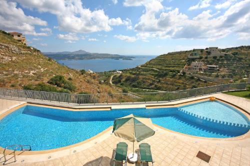 a swimming pool with a view of a hill at Aptera Paradise With Sea View in Megála Khoráfia