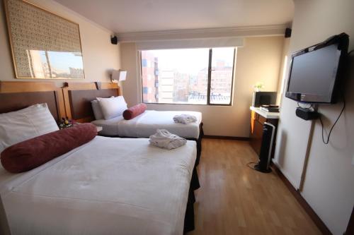 a hotel room with two beds and a flat screen tv at Lancaster House in Bogotá