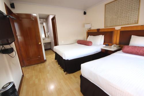 a hotel room with two beds and a flat screen tv at Lancaster House in Bogotá