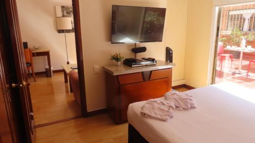 a bedroom with a bed and a television on a dresser at Lancaster House in Bogotá