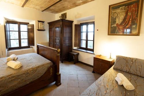 a bedroom with a bed and a dresser and windows at GiuMa Tuscany Historic Country House with Roof Terrace near Saturnia Spa in Montemerano