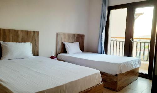 two beds in a room with a window at Aldau Sunset in Hurghada