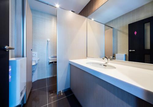 a bathroom with a sink and a mirror at Daiwa Roynet Hotel Kokura Ekimae in Kitakyushu