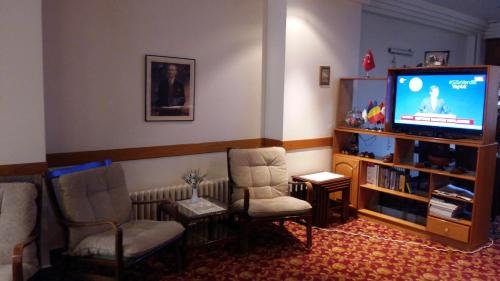 a living room with two chairs and a flat screen tv at Hotel Cesmeli in Bursa