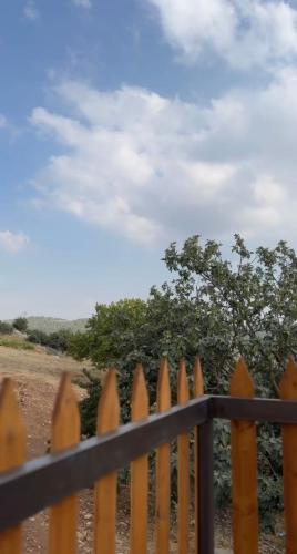a wooden picket fence with a tree in the background at Alsaba Huts in Ajloun