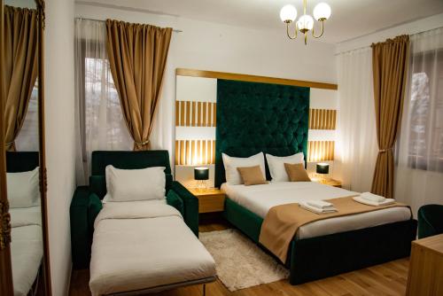 a bedroom with two beds and a green headboard at Zestrea Maramureșului Săpânța in Săpînţa