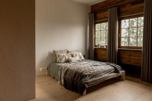 a bedroom with a bed and two windows at Country homestead in Abava Valley "Viļņi" in Tojāti