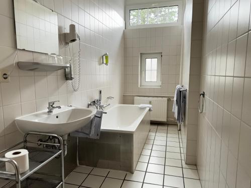 a white bathroom with a sink and a tub at Hotel Zu den Linden in Dresden