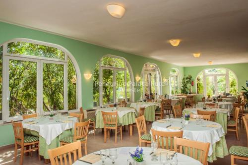 a restaurant with white tables and chairs and windows at Pellegrino Palace Hotel in Vieste