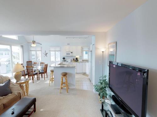 Una sala de estar con un televisor grande y una cocina. en Oceanside Beach Badges Wifi Ocean Views From The Decks! 5Th From The Beach Surf City 14016, en Surf City