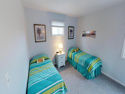 Un dormitorio con dos camas y una mesa con lámpara. en Oceanside Beach Badges Wifi Ocean Views From The Decks! 5Th From The Beach Surf City 14016, en Surf City