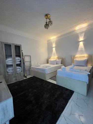 a white bedroom with two beds and a mirror at Triple Garden Studios and apartments in Cairo