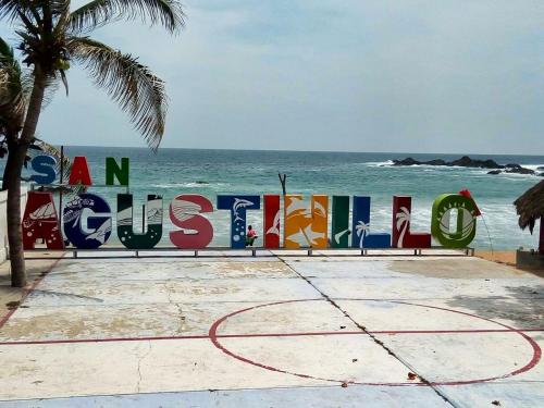 a sign on the beach with the ocean in the background at Cabañas Uma 1 in San Agustinillo