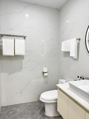 a white bathroom with a toilet and a sink at JJY Apartment in Nadi