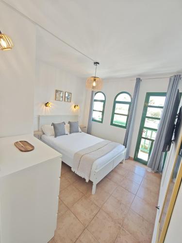 a white bedroom with a white bed and some windows at Paradise Tropical Sun Maspalomas in San Bartolomé