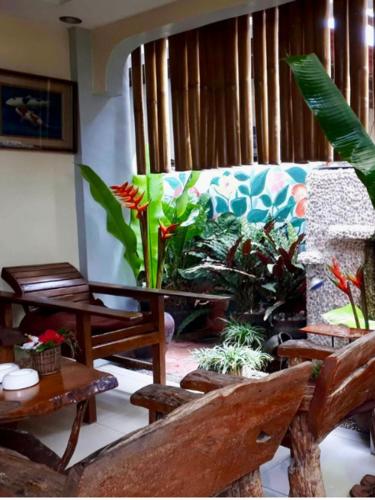 a living room with wooden chairs and plants at Casa Maria in Davao City