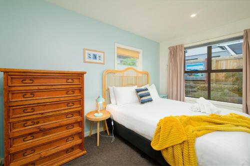 a bedroom with a bed and a dresser and a window at Classic Charm Sea & Mountain Views in Kaikoura