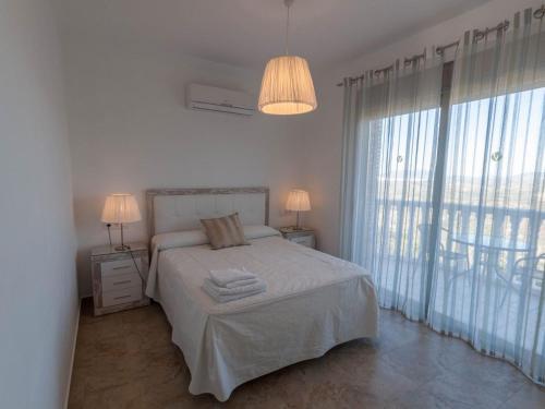 Un dormitorio blanco con una cama y una ventana grande. en Villa 12 by Villamya, en El Gastor