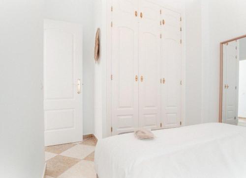 a white bedroom with white cabinets and a cat sitting on a bed at Rincón del Guadiana in Ayamonte
