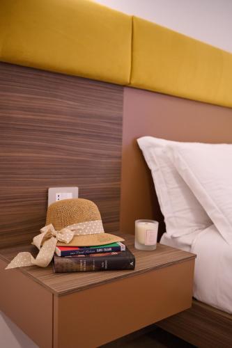 a bed with a table with books and a hat on it at San Nicola Rooms Siracusa in Siracusa
