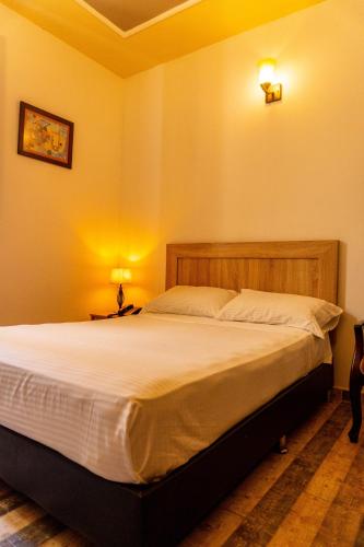 a bedroom with a large bed with white sheets at LAMACA - Hotel & Restaurante in Buga