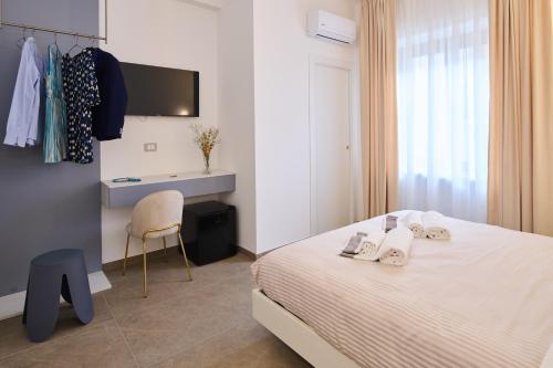 a bedroom with a bed and a desk and a chair at San Nicola Rooms Siracusa in Siracusa