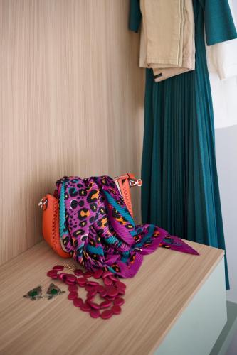a bag sitting on top of a bed with flowers at San Nicola Rooms Siracusa in Siracusa