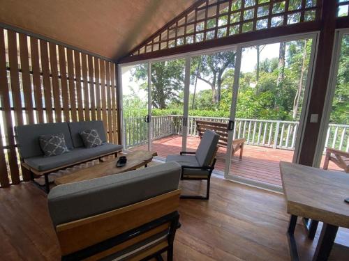 a screened in porch with a couch and a table at Casa MILUCO Maison privée vue sur mer in Puerto Viejo