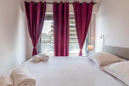 - une chambre dotée d'une grande fenêtre avec des rideaux rouges dans l'établissement LB Vacation Rentals I High Floor Sea View 2Br Apt with Balcony & Garage, à Cannes