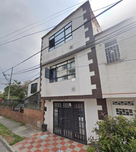 a white house with black doors on a street at La Ponderosa Studio Apartment in Bogotá