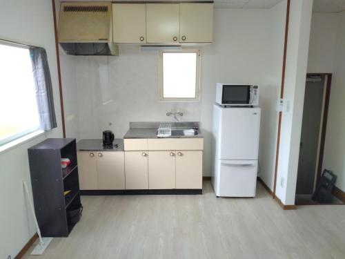 a kitchen with a white refrigerator and a microwave at ナガエベース in Hyuga
