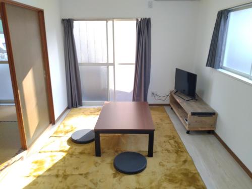 a living room with a table and a tv at ナガエベース in Hyuga