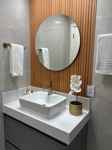a bathroom with a white sink and a mirror at Flat Premium -Acesso a pé ao shopping Center vale - Edifício Summit (Ar condicionado) in São José dos Campos
