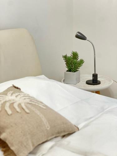 a bed with a lamp and a plant on a table at Vida Real Estate Feucht in Feucht
