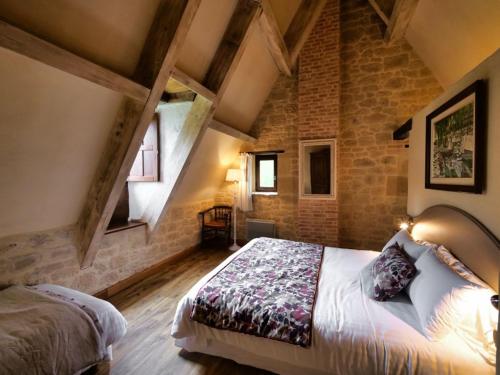 une chambre avec un grand lit dans un mur de pierre dans l'établissement Les Granges Hautes, maisons de vacances, proches de Sarlat avec piscine, parc,, à Saint-Crépin-et-Carlucet