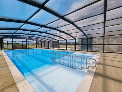 une grande piscine avec un plafond de verre dans l'établissement Cottage du Lac 63, à Olonzac