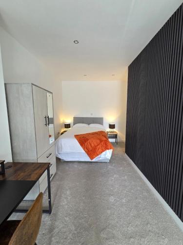 a bedroom with a bed with an orange blanket on it at Spacious New Studio in Blackburn Town Centre in Blackburn