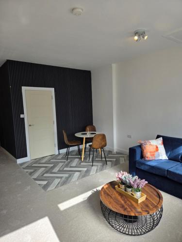 a living room with a blue couch and a table at Spacious New Studio in Blackburn Town Centre in Blackburn
